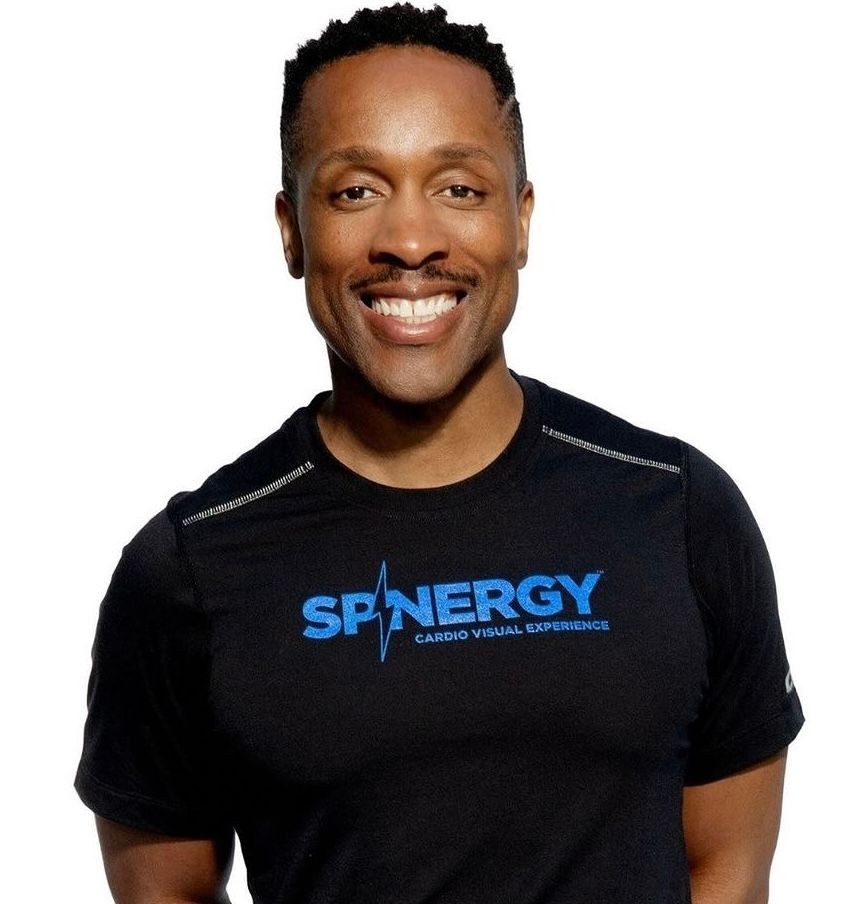 Person wearing a black shirt with the blue 'Spinergy Cardio Visual Experience' logo.